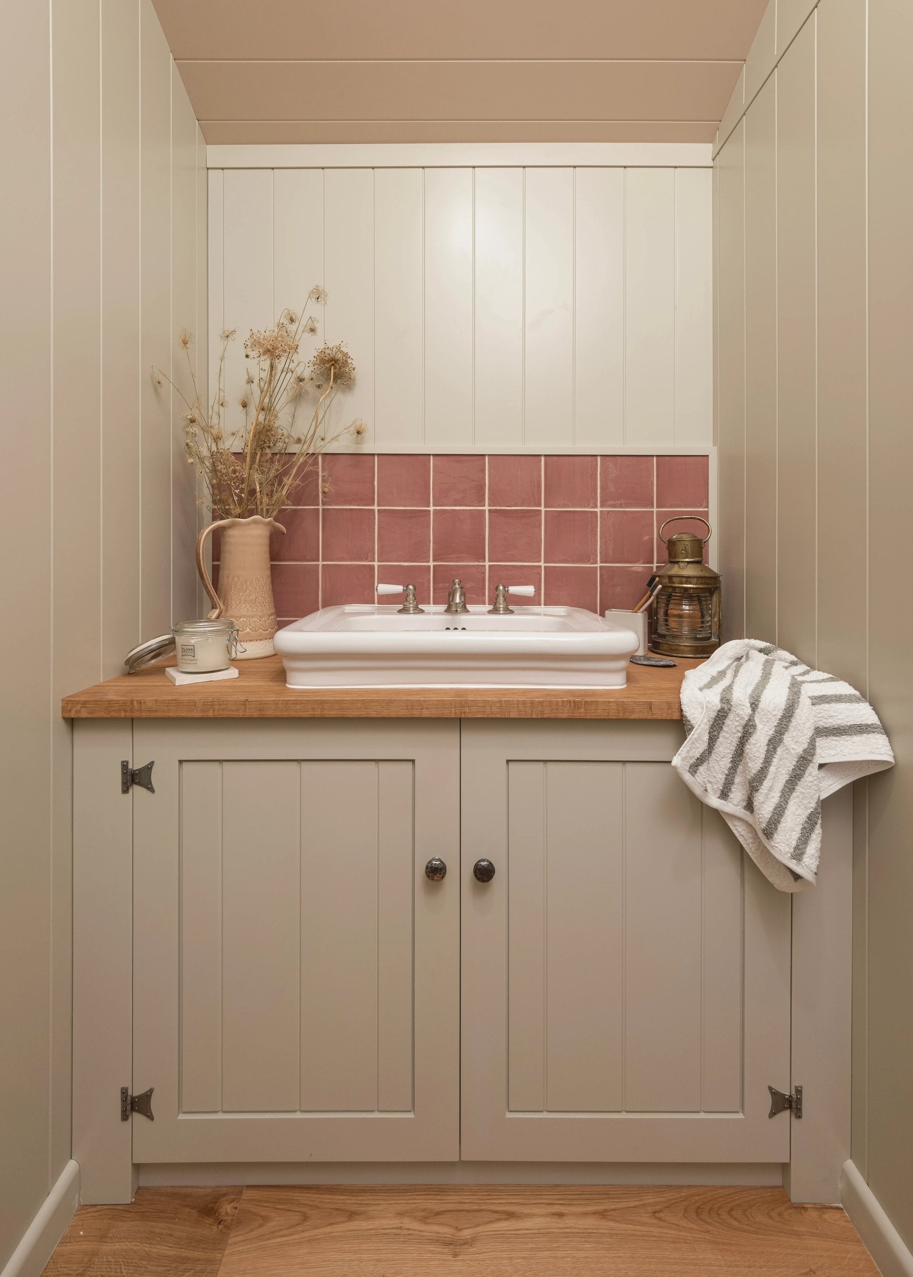 Bathroom with wooden vanity, sink, and pink tiled wall.